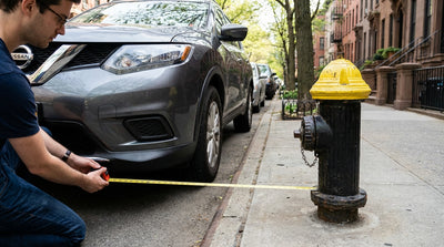 A red fire hydrant on a sidewalk with a car rental parked on the street in New York City