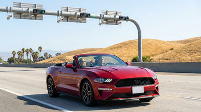 A white car rental driving down a sunny California freeway lined with tall palm trees