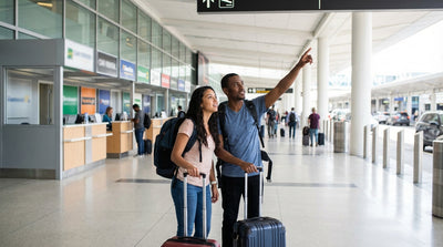 A brightly lit row of shared car rental counters inside a busy New York airport terminal