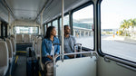 Passengers boarding a car rental shuttle bus outside a Houston airport terminal in Texas