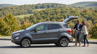 A car rental drives down a scenic road surrounded by colorful autumn foliage on a sunny day in Pennsylvania