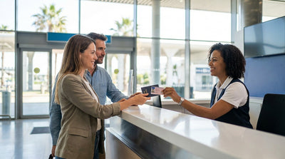 A traveler presents their ID at a car rental counter inside the busy Los Angeles LAX airport