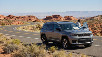 A modern car hire driving on a scenic highway through the desert landscape outside of Las Vegas at sunrise