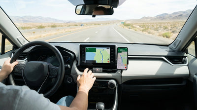 A smartphone with a map app mounted to the dashboard of a US car hire driving on a scenic open road