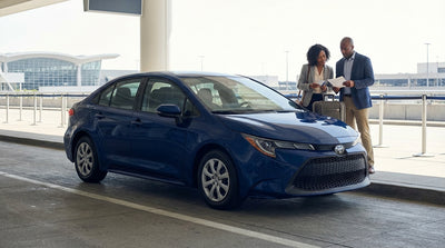 A modern car rental driving on a busy street in New York City with yellow taxis and skyscrapers in the background