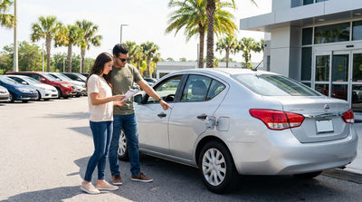 Driver holding a fuel pump nozzle preparing to fill up a white car rental in Orlando