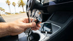 Smartphone charging via USB cable on the dashboard of a car rental driving on a scenic road in California