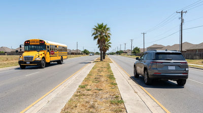 A yellow school bus with flashing lights on a divided Texas highway, seen from the driver's seat of a car hire