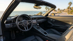 Hand shifting a manual gear stick inside a car rental on a scenic California highway