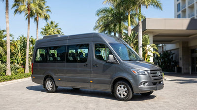 A white 10-passenger van car rental parked on a sunny street with palm trees in Miami