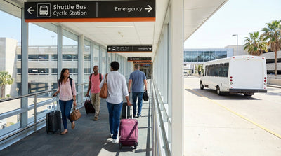 A traveler with luggage follows overhead signs for the car rental shuttle at DFW Airport in Texas