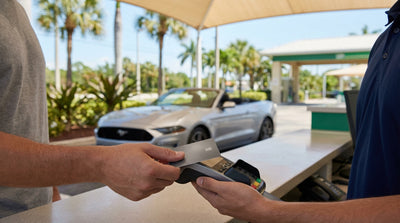 A shiny red car hire convertible driving down a scenic highway lined with palm trees in sunny Florida