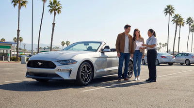 A convertible car rental drives along the sunny, winding Pacific Coast Highway in California