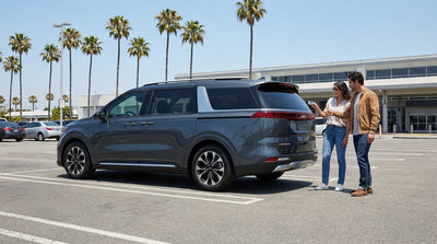A modern white SUV car rental driving on a scenic coastal road in California with ocean views