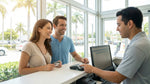 Two friends smile while finalizing their car rental agreement with an agent at a desk in Miami