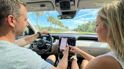 A person's hands on the steering wheel of a car hire, with a sunny Florida road seen through the windshield