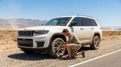 A red car hire drives down a long desert highway leading away from Las Vegas toward distant mountains
