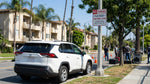 A car hire vehicle parked on a sunny Los Angeles street next to a 'No Parking' sign for a film shoot