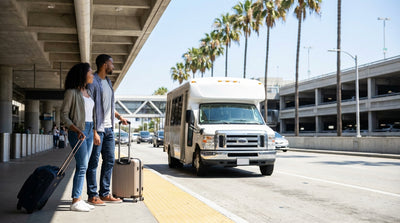 Travelers with luggage wait for the car hire shuttle bus outside an LAX terminal in Los Angeles