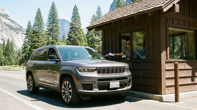 A car rental parked at a scenic overlook with a view of Yosemite Valley and Half Dome in California