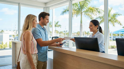 A red convertible car hire driving down a sunny highway lined with palm trees in Florida