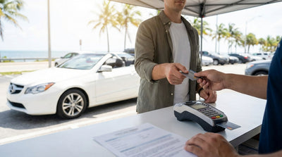 A white convertible for car hire parked on a sun-drenched street with palm trees in Miami