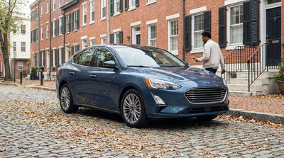A person using a smartphone to unlock their car rental on a tree-lined street in Pennsylvania