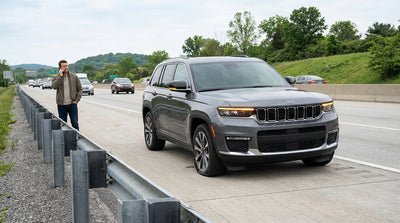 A car hire with a flat tire is pulled over on the shoulder of a busy highway in Pennsylvania as traffic speeds past
