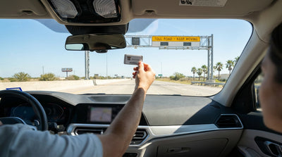A car rental drives under an electronic toll gantry on a multi-lane highway in Texas