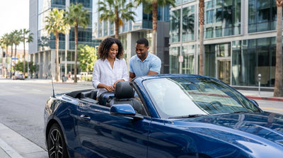 A modern car rental drives down a palm-tree-lined street in sunny downtown Los Angeles