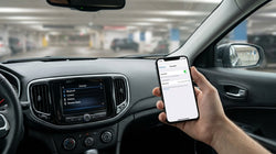 Person holding a smartphone near a dashboard touchscreen inside a New York car rental
