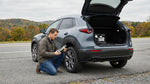 Driver using a tyre sealant kit on a Pennsylvania car hire parked on a scenic forest road
