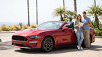 Woman driving a car rental along a sunny palm tree lined street in California