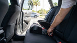 A mother installs a child safety seat in the backseat of a family car rental in sunny Florida