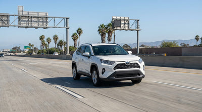 A car rental drives on a sunny Los Angeles freeway towards the overhead signs for the Metro ExpressLanes