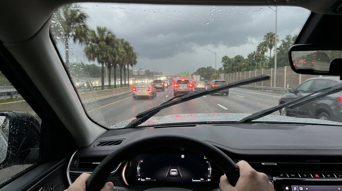 A car hire navigates a wet Orlando highway with traffic during a dramatic afternoon thunderstorm