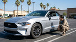 Modern white car rental parked along a sunny palm tree-lined street in California