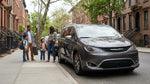 Two passengers looking out the window of a car rental parked on a New York street
