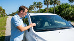 A close-up of a rock chip crack on the windscreen of a car hire parked under palm trees in Florida