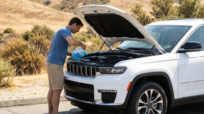 A driver looking under the hood of a modern car hire vehicle parked on the side of a sunny California highway