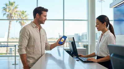 A person checks their phone before getting into their car hire vehicle on a sunny street with palm trees in Miami