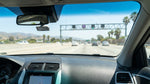 A car rental drives under a FasTrak toll lane sign on a sunny multi-lane California freeway