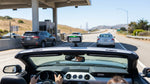 White car rental driving across the Golden Gate Bridge in San Francisco under a blue sky
