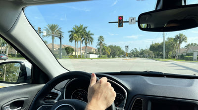 A hire car waits at a red arrow traffic light at a sunny intersection in Florida