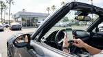 Person holding a smartphone showing a map inside a car rental on a sunny California highway