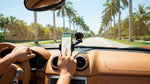 Smartphone attached to a dashboard mount inside a car rental driving on a sunny Florida highway