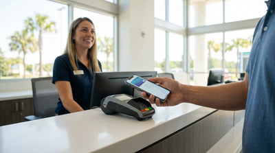 A person using a smartphone to make a contactless payment at a car hire desk in an Orlando airport