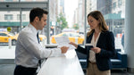Customer handing paperwork to an agent at a car rental desk in New York