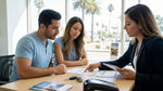 A customer receiving keys at a car rental desk with sunny California palm trees outside