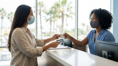 A person hands their driver's license to an agent at a car rental counter in a bright California airport